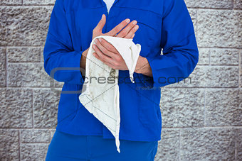 Composite image of cropped image of mechanic wiping hand with napkin