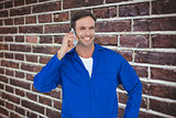 Composite image of mechanic using mobile phone over white background