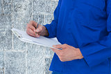 Composite image of mechanic writing notes on clipboard