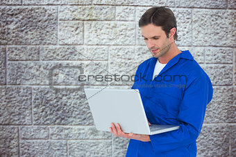 Composite image of mechanic using laptop over white background