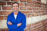 Composite image of happy mechanic with arms crossed over white background