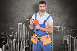 Composite image of confident male carpenter in overall holding drill machine
