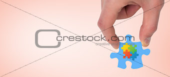 Composite image of hand holding jigsaw piece