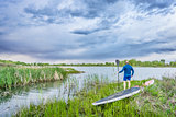 senior paddler with SUP paddleboar watching stormy sky