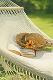 Straw hat and book on lace hammock