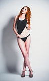 Studio fashion shot of sexy young redhead woman in shirt and panties. Full length
