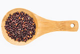 black quinoa grain on wooden spoon
