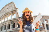 Woman making victory sign in Rome near Colosseum holding map