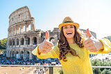 Smiling woman giving two thumbs up at Colosseum in Rome