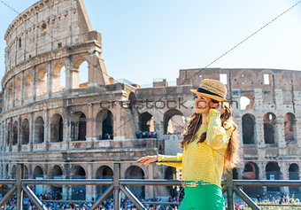 Woman standing near Colosseum in Rome listening to music