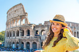 Woman standing near Colosseum in Rome adjusting earbud