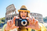 Laughing woman looks up from taking photo with Colosseum behind