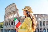 Woman holding flag looking into distance at Colosseum in Rome