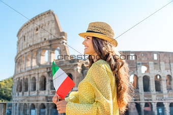 Woman holding flag looking into distance at Colosseum in Rome