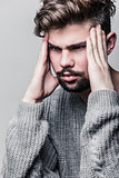 Portrait of a young man in gray pullover. Headache