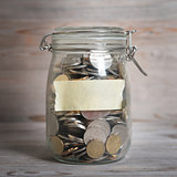 Coins in glass money jar with blank label