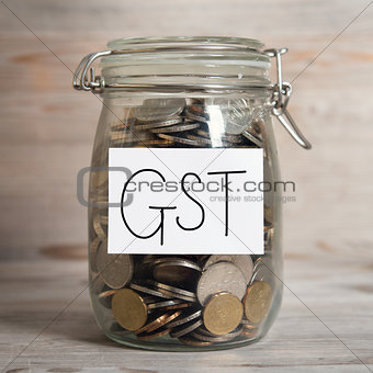 Coins in glass money jar with gst label