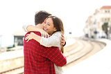 Couple hugging happy in a train station