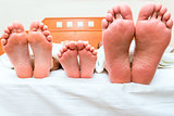 family of three people sleeping in one bed, feet close-up