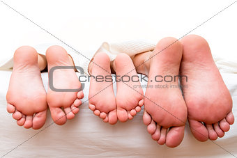 feet of parents and child on the bed close-up