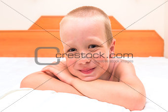 mischievous preschooler resting in bed and smiling