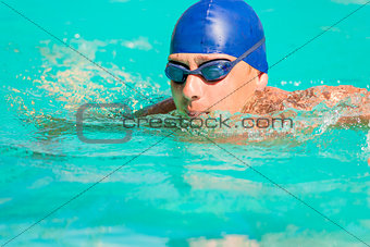 swimmer in blue cap and goggles swimming in the pool