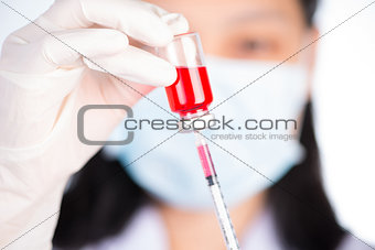 Nurse fills syringe from injection vial on white