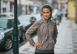 Woman runner wearing rain gear stopped and feeling unmotivated