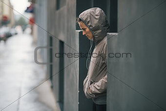 Woman jogger wearing rain gear wondering how long it will rain