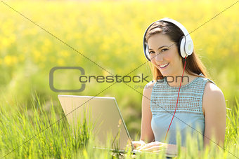 Woman with a laptop and headphones in a field