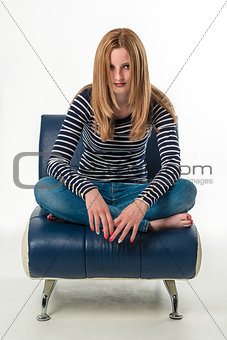 Beautiful stylish young woman sitting cross-legged on a couch