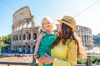 Smiling mother and daughter with Colosseum in background