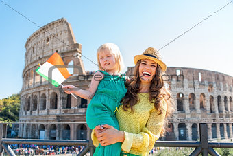 Smiling mother holding daughter with Italian flag and Colosseum