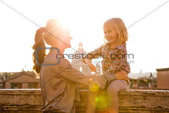 Mother holding daughter sitting on ledge in Rome