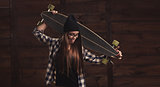 Hipster girl in glasses and with a longboard