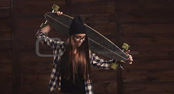 Hipster girl in glasses and with a longboard