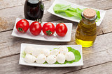 Tomatoes, mozzarella and green salad leaves with condiments