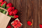 Red tulips bouquet in bag over wood