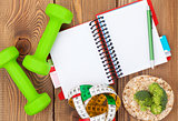 Dumbells, tape measure, healthy food and notepad for copy space.