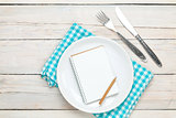Notepad for recipe over empty plate and silverware