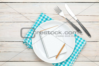 Notepad for recipe over empty plate and silverware