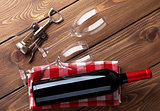 Red wine bottle, glasses and corkscrew on wooden table