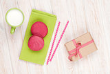 Colorful macarons, cup of milk and gift box