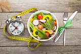 Fresh healthy salad and measuring tape on wooden table