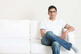Good looking young Indian guy sitting on sofa 