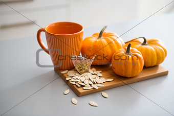 A study in pumpkin colours including a mug, seeds, and pumpkins
