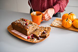 Sliced home-made loaf of pumpkin bread, woman's hands and tea