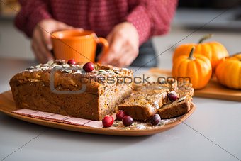Closeup of fruit and seed loaf with woman's hands holding mug