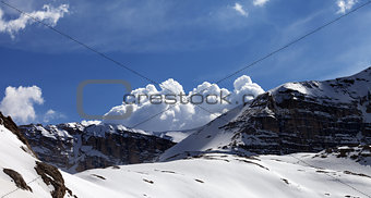 Panoramic view on snow rocks and cloudy blue sky