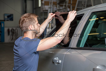 Applying tinting foil onto a car window in a workshop